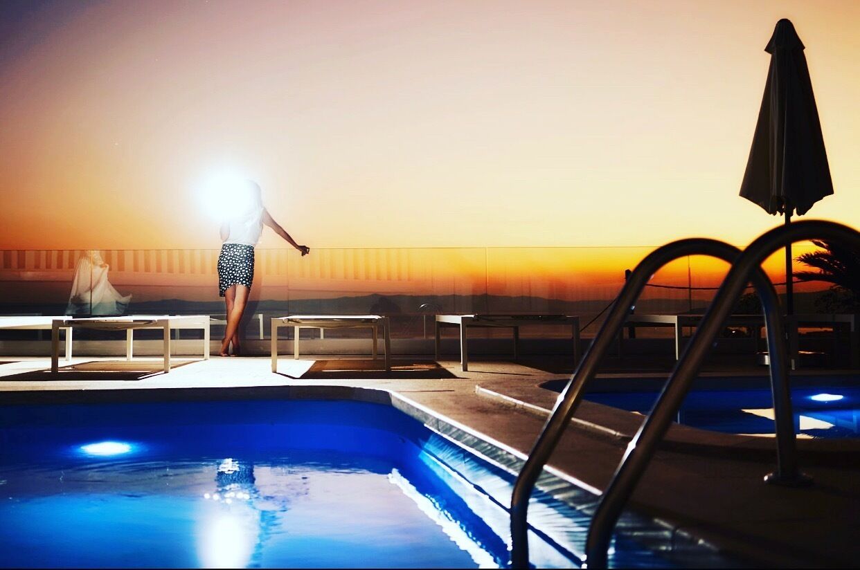 A swimming pool with a sunset view, a lifeguard chair, and a lounge chair.