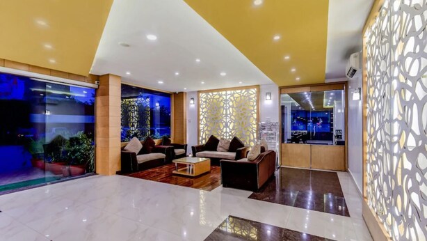 Een moderne lobby met een marmeren vloer, banken en een decoratieve scheidingswand.