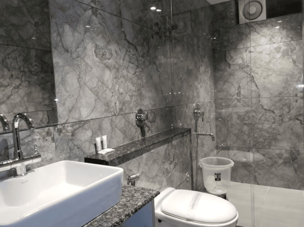 A modern bathroom with a marble sink, a toilet, and a shower area.