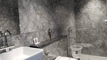 A modern bathroom with a marble sink, a toilet, and a shower area.