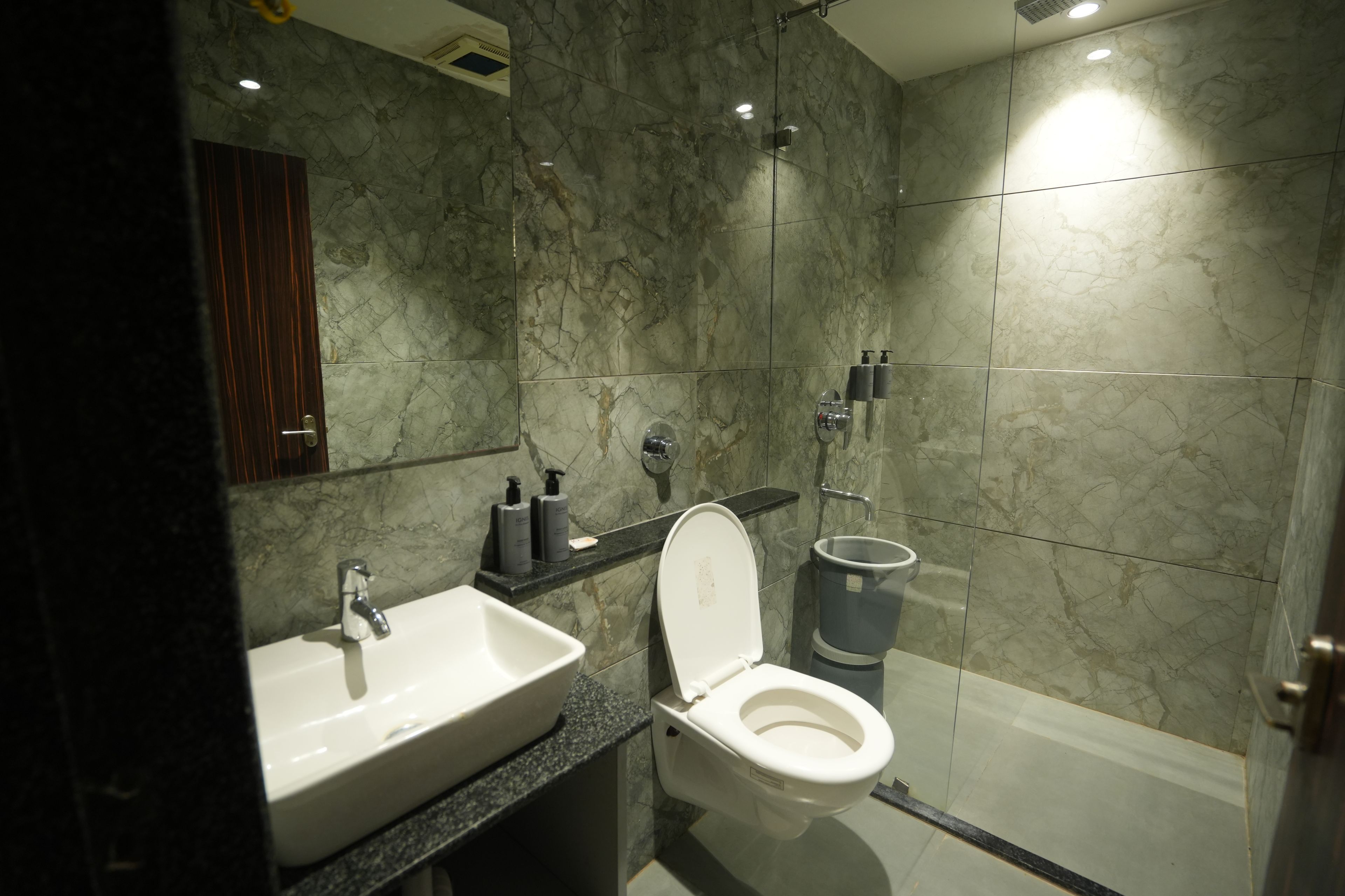 A modern bathroom with a marble sink, toilet, and shower.
