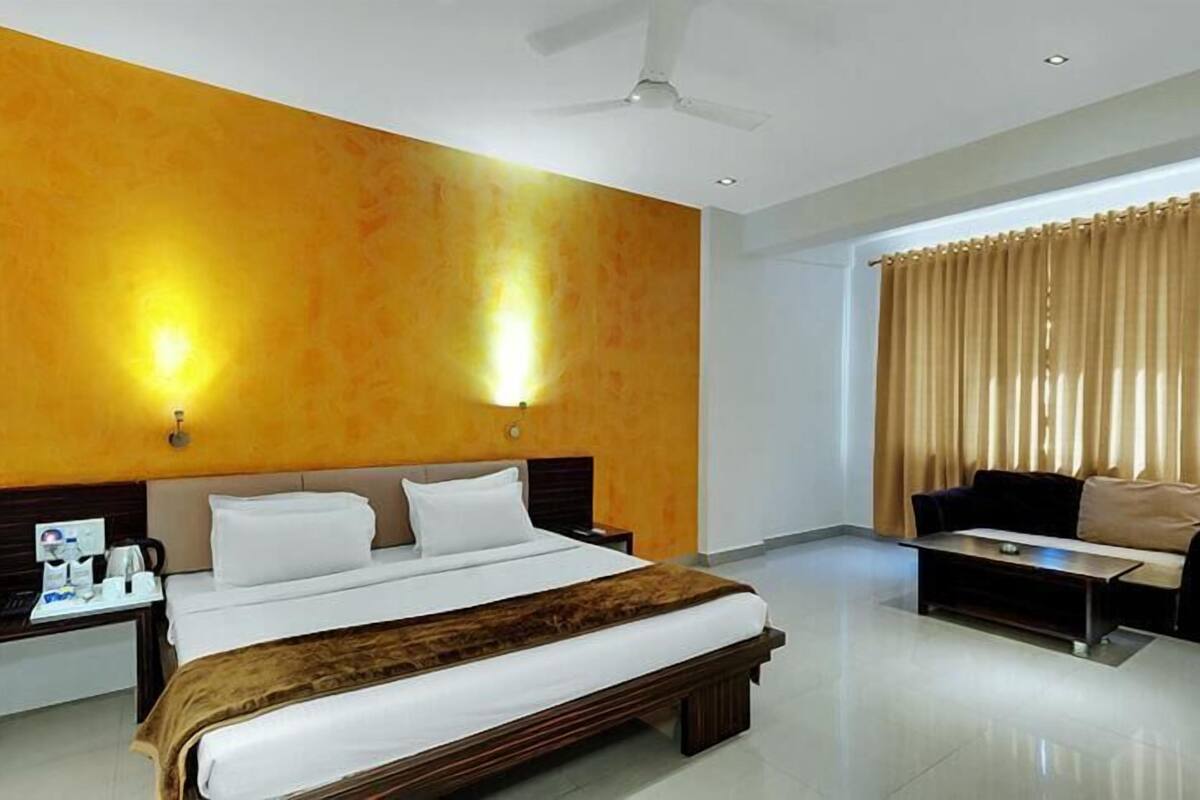 Une chambre d’hôtel avec un grand lit, un bureau avec une chaise, un canapé et un ventilateur de plafond.