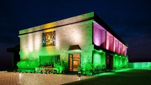 Een modern gebouw met een grote verlichte reclameborden, een bakstenen gevel en een entreezone met groene verlichting.