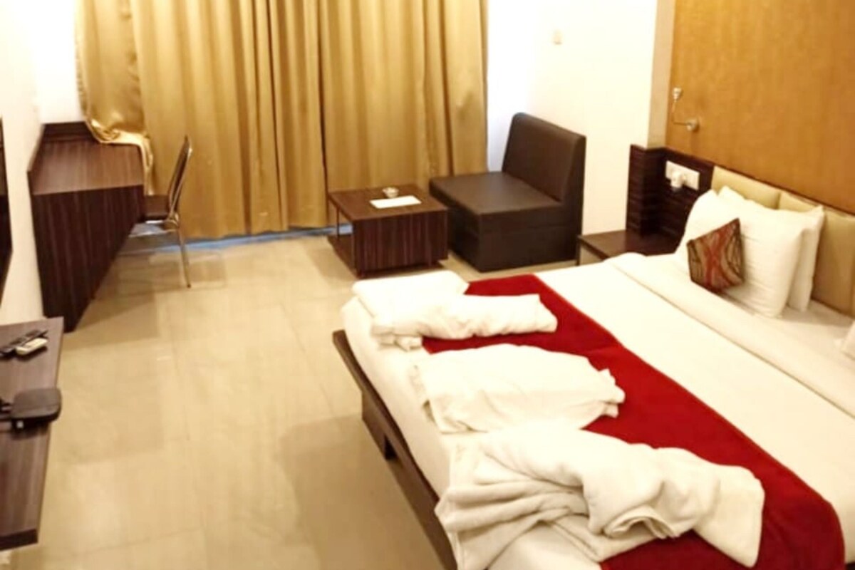 A deluxe room with a bed, a chair, a desk, and a wardrobe.