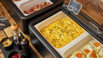 Ein Buffet mit Rührei, Speck und einem Schild, das Rührei anzeigt.