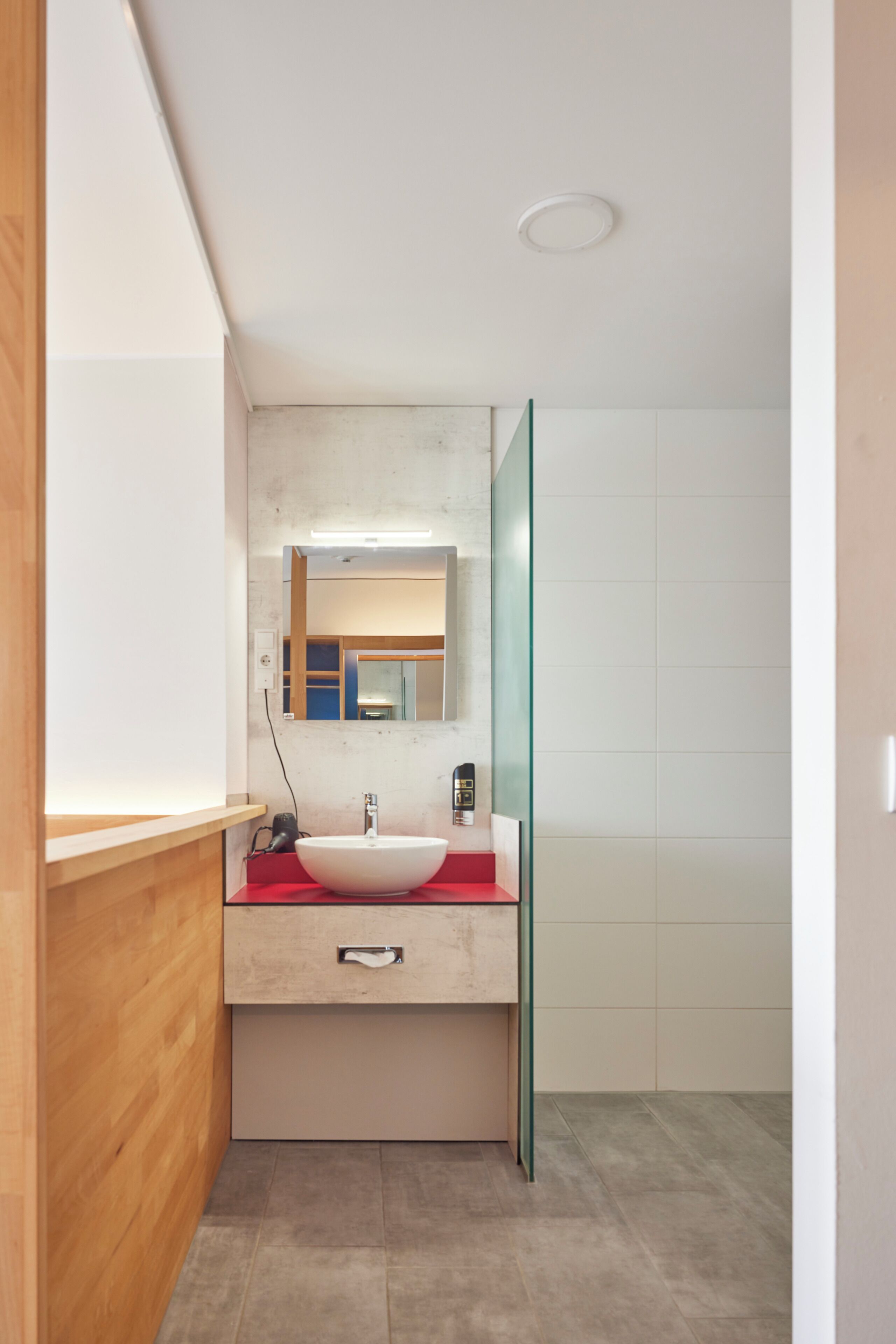 A modern bathroom with a white sink, a mirror, and a glass shower enclosure.