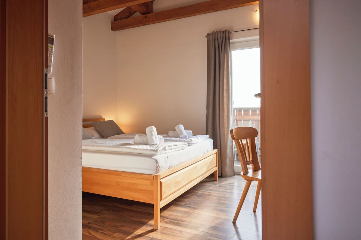 Une chambre à coucher avec un lit en bois, une chaise et une fenêtre avec des rideaux.