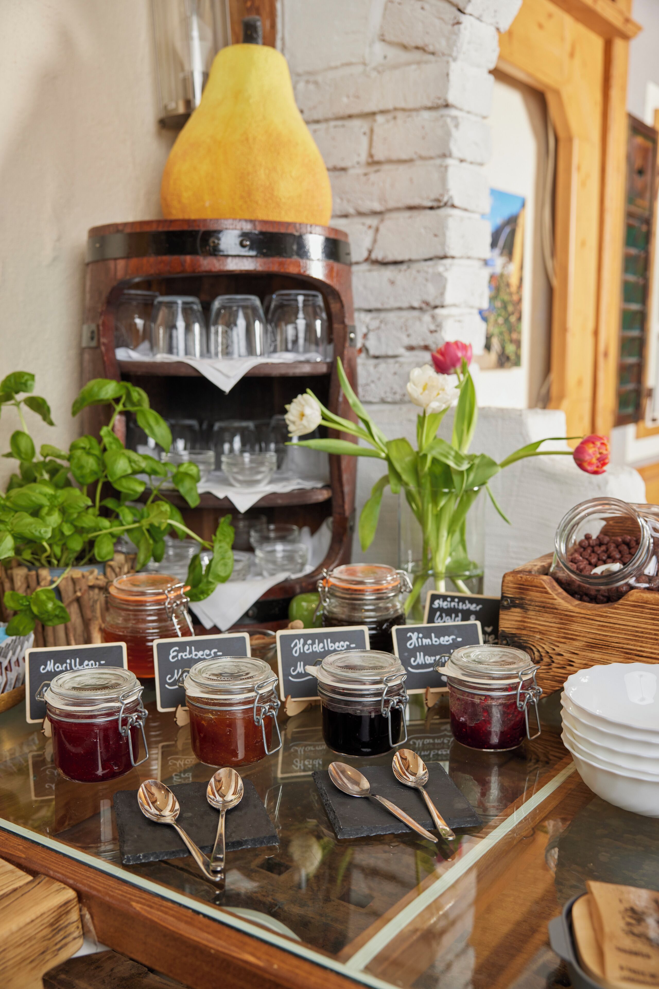 A breakfast buffet with various jams and a pear on display.