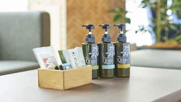 A wooden box with a few items and three bottles of Olive Green hair conditioner on a table.