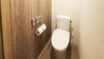 Un baño con puerta de madera, un inodoro y un dispensador de toallas de papel.