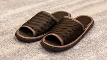 A pair of brown mesh slippers on a textured carpet.