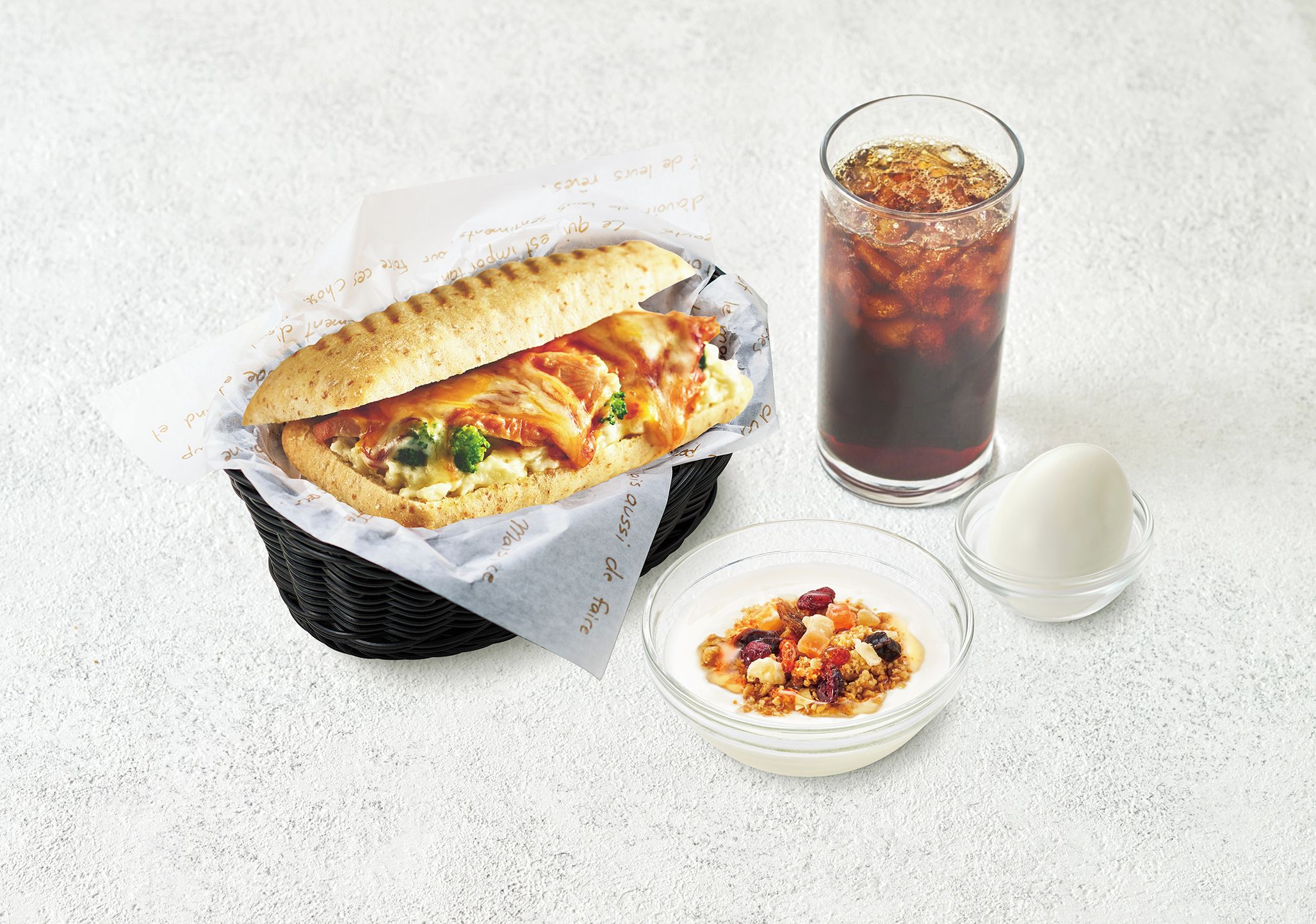 A meal consisting of a sandwich, a glass of iced drink, and a bowl of cereal with milk.