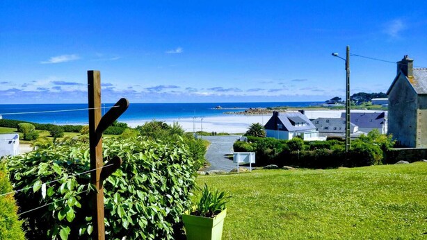 Une vue sur la côte, avec un premier plan composé d’une pelouse, un chemin pavé et des maisons offrant une vue sur la mer.