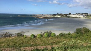 Un paysage côtier avec une plage, l’océan et des bâtiments en arrière-plan.