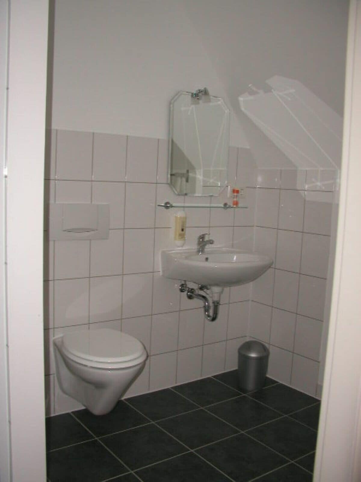 Un baño pequeño y limpio con inodoro, lavamanos y espejo.
