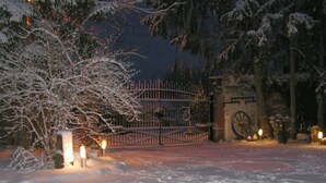Schneebedeckte Landschaft mit einem verschlossenen Eingang, einem Glockenturm und einem mit Schnee bedeckten Baum.