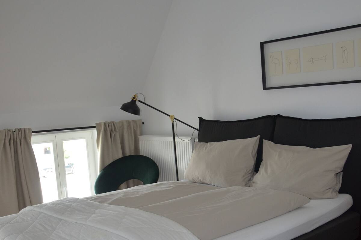 A bedroom with a large bed, a desk, and a chair.