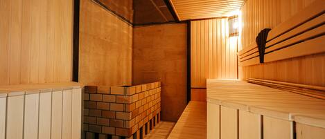 A sauna with wooden benches and a brick wall.
