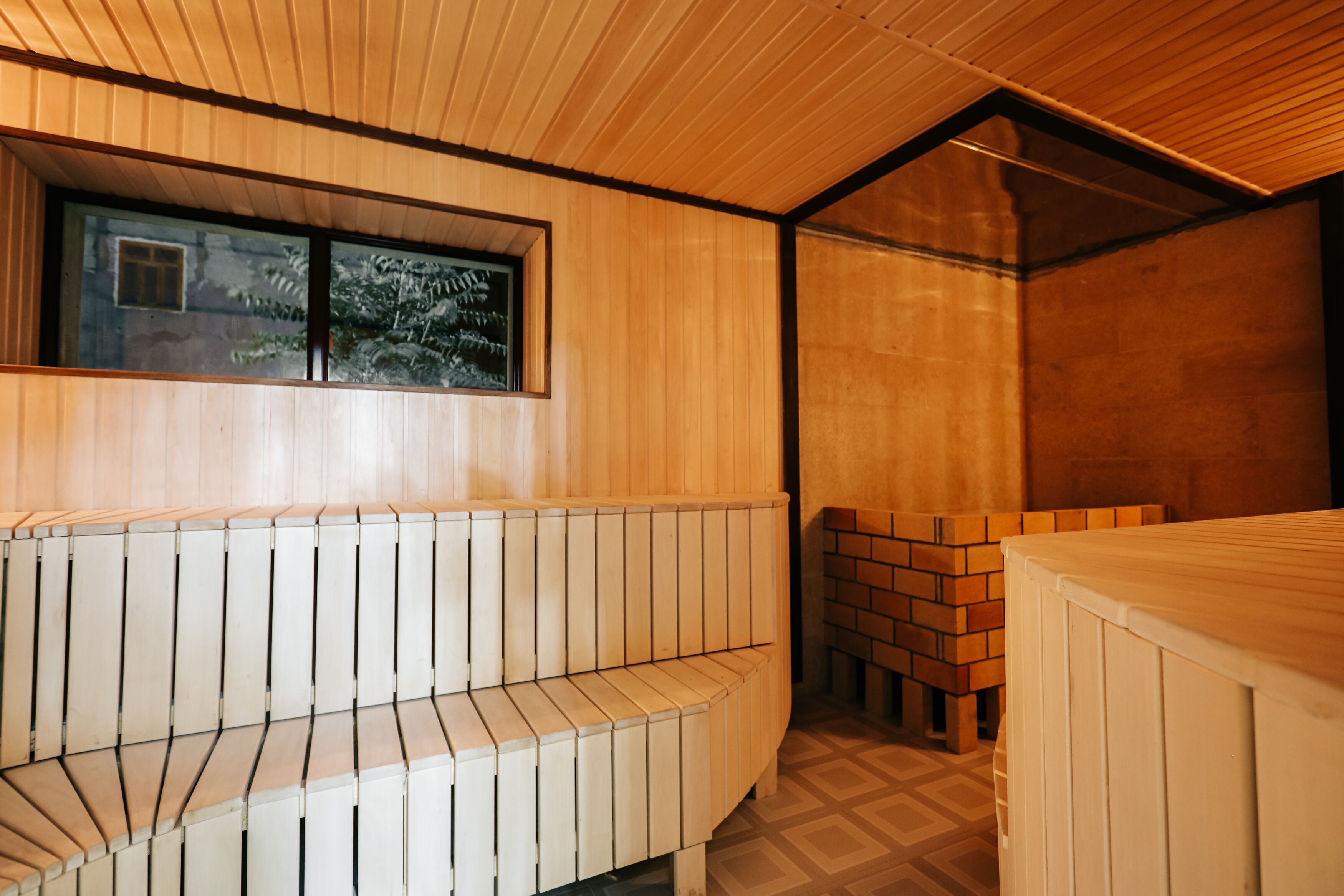 A sauna with wooden benches and a brick wall.
