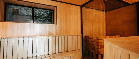 A sauna with wooden benches and a brick wall.