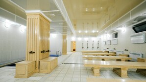 Amplia habitación con bancos de madera, una columna central y piso de baldosas.