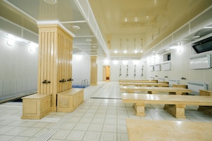 Amplia habitación con bancos de madera, una columna central y piso de baldosas.