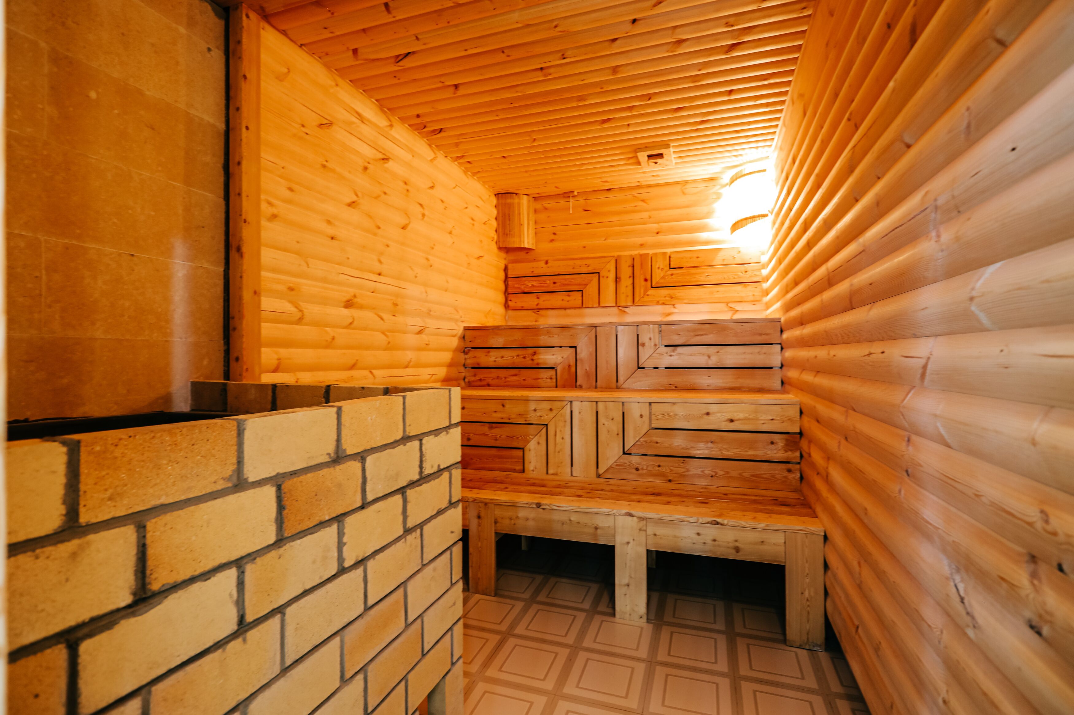 Ein Blockhaus-Interieur mit Backsteinwand, Holzbänken und schrägverdeckter Decke.