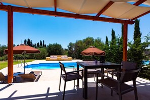 Un patio al aire libre con piscina, pérgola de madera y zona de estar.