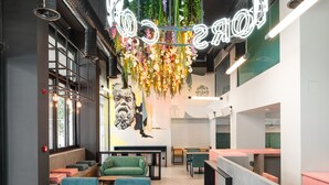 A modern interior with hexagonal flooring, green seating, a neon sign, and a green wall with plants.