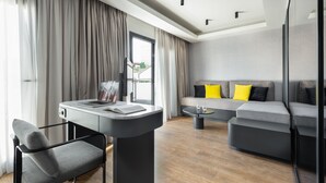 A modern living room with a sofa, a coffee table, a desk with a chair, and large windows with curtains.