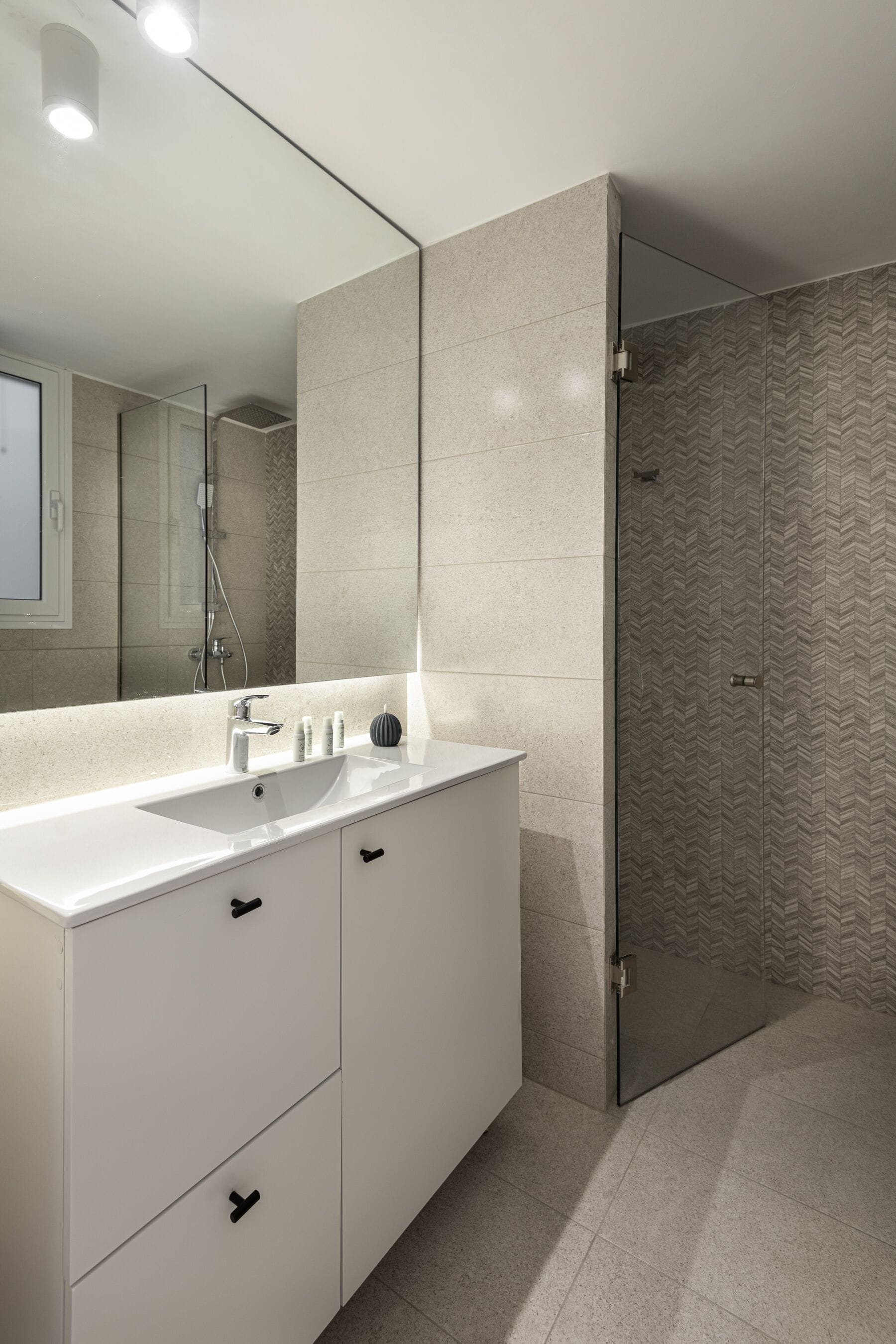 A modern bathroom with a white vanity, a large mirror, and a shower area with a glass door.