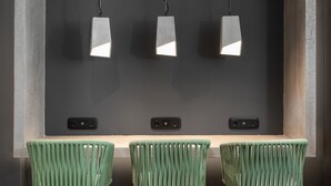 A modern bar area with three green bar stools and a wooden counter.