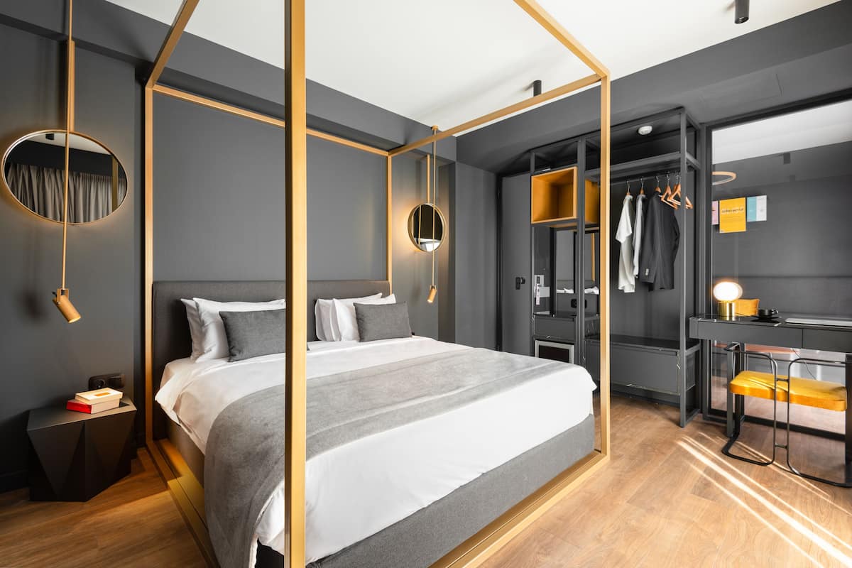 A modern bedroom with a four-poster bed, a walk-in closet, and a desk with a chair.
