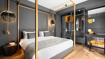 A modern bedroom with a four-poster bed, a walk-in closet, and a desk with a chair.