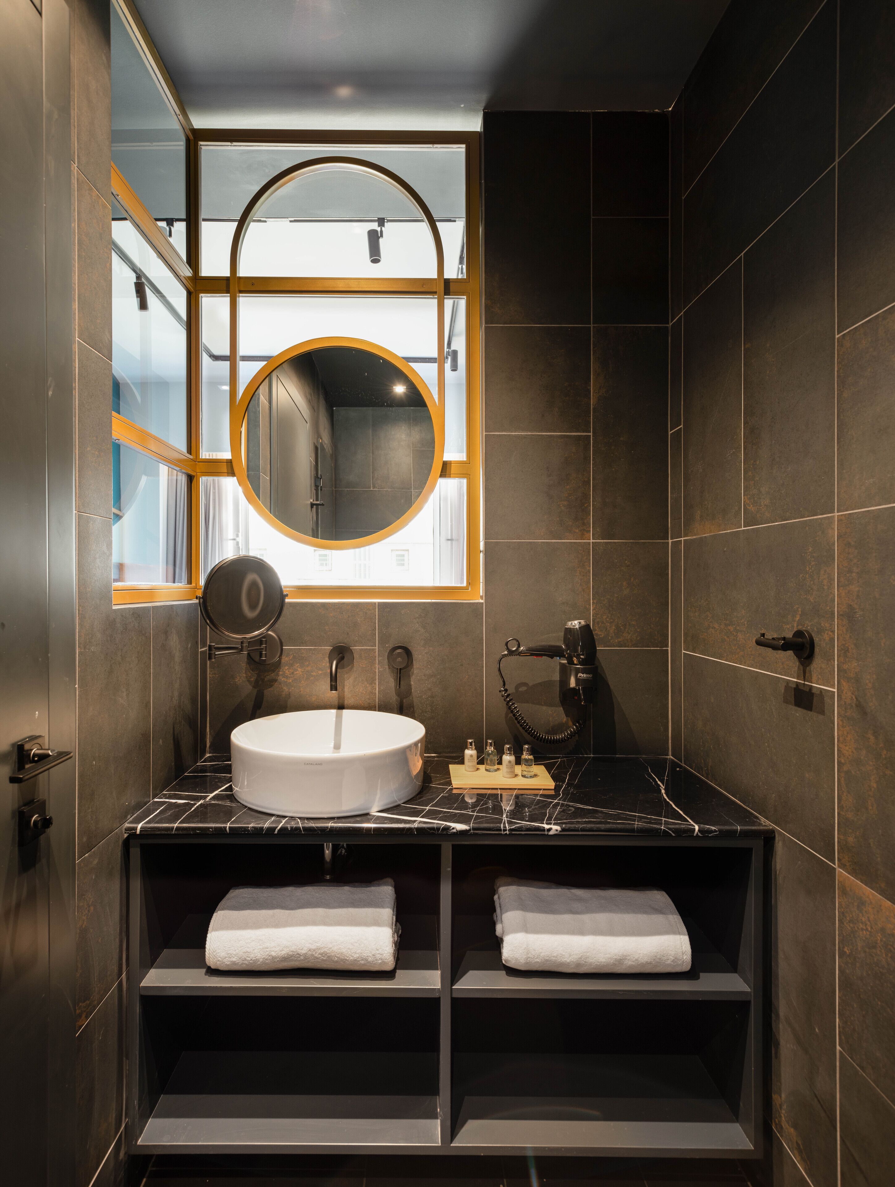 A modern bathroom with a round mirror, a sink, and a hairdryer.