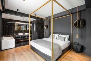 Quarto moderno com uma cama de dossel, um espelho grande, um relógio de parede redondo e uma mesinha de cabeceira.