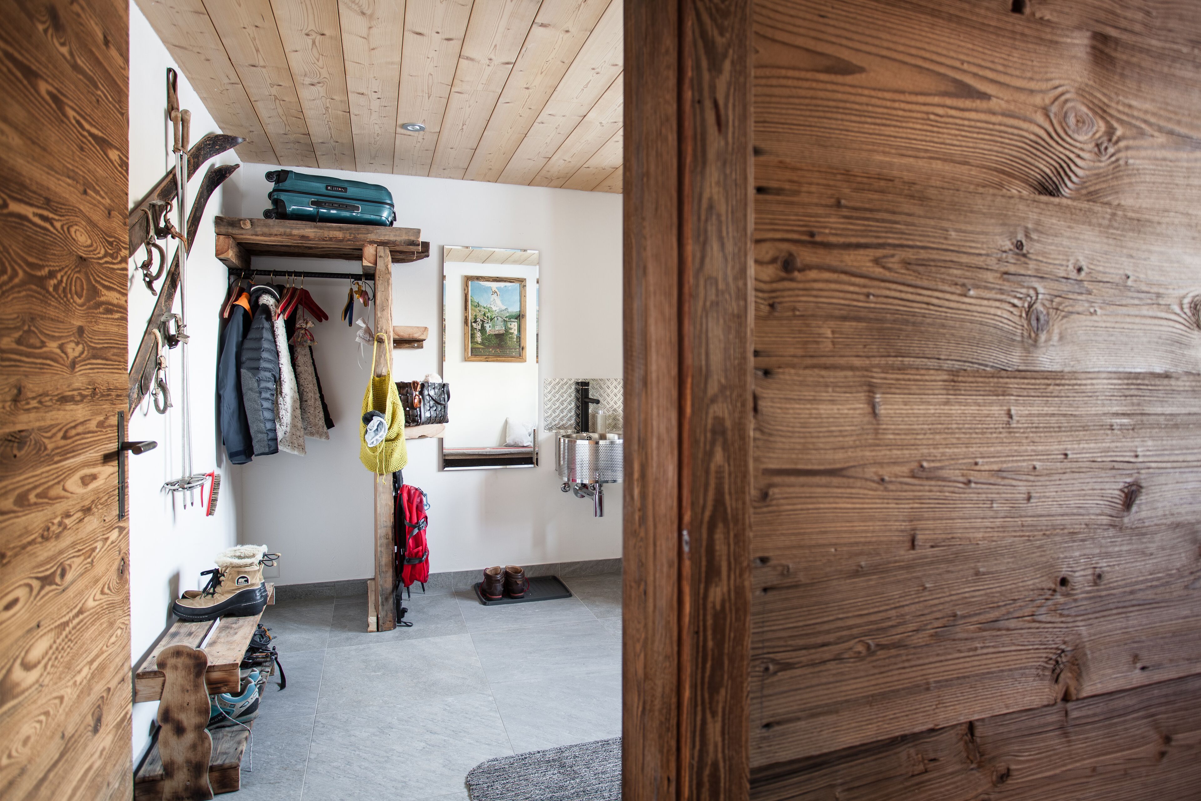 A wooden interior with a bench, boots, and a coat rack.