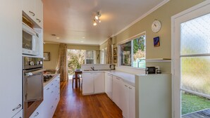 Une cuisine moderne avec des armoires blanches, un four à micro-ondes encastré et une cuisinière à gaz. Une fenêtre offre une vue sur l’extérieur.