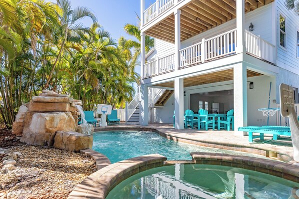 A two-story building with a pool, outdoor seating, and a staircase leading to the upper level.