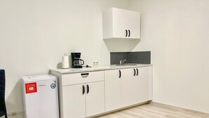 A compact kitchenette with a refrigerator, coffee maker, and sink. - Cardinal Central Apartment (Satu Mare)