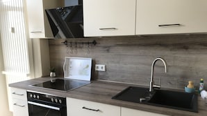 Una cocina moderna con horno empotrado, placa de cocina, fregadero y salpicadero de madera.