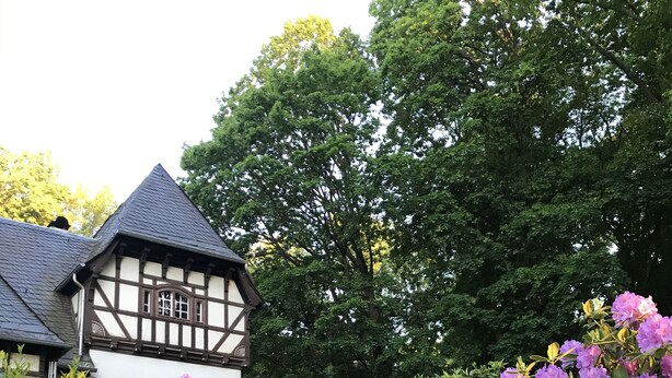Un edificio de estilo Tudor con un techo empinado y fachada blanca con entramado de madera oscura.