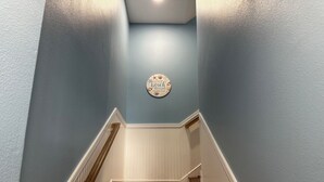 A wooden staircase with white wainscoting and a blue wall.