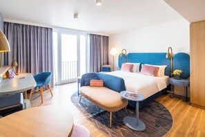 Une chambre d’hôtel moderne avec un grand lit, un bureau, une chaise et une petite table.