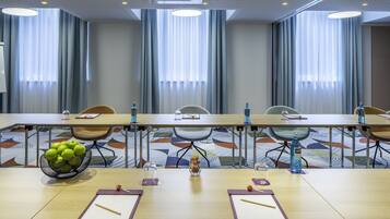Une salle de conférence avec une longue table, des chaises, un panier de fruits et des bouteilles d’eau.