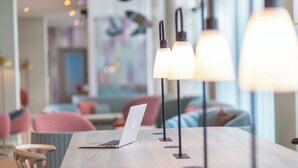 A modern dining area with a laptop on a table, pendant lights, and a view of the interior. - Capri by Fraser Leipzig (Leipzig)