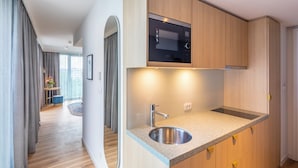 A modern kitchen with a built-in microwave, stainless steel sink, and wooden cabinets. - Capri by Fraser Leipzig (Leipzig)