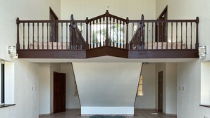 A spacious interior with a central open area, a balcony with a railing, and a tiled floor. - Bahia Bay Resort (Key Largo)