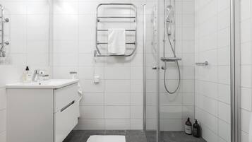 Une salle de bain moderne avec une douche à parois de verre, un lavabo blanc et un porte-serviettes.