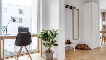 A modern room with a desk, chair, potted plant, wardrobe, and a view of the outside.